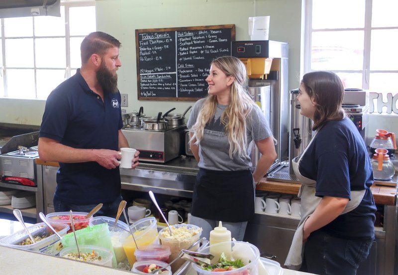 Cafeteria, Restaurant, Man, Person. Text: Today&#039;s Specials -Mashed Potatoes Gravy -Scalloped Potetoes -Green Beans BUNN Cold Sides -Cucumbers Onions -House Green Salad TH ED &amp; ROOTED