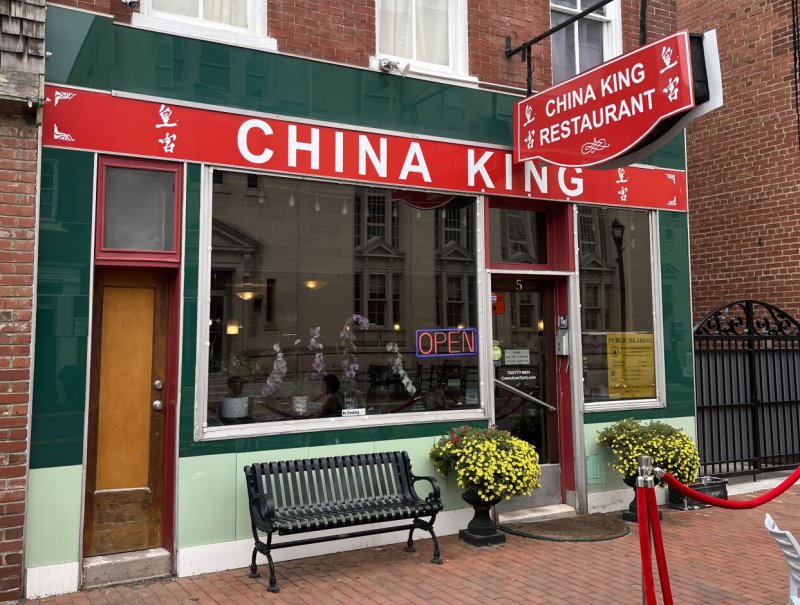 Potted Plant, Bench, Furniture, Building. Text: CHINA KING CHINA KING RESTAURANT 5 OPEN PUBLIC HEARING