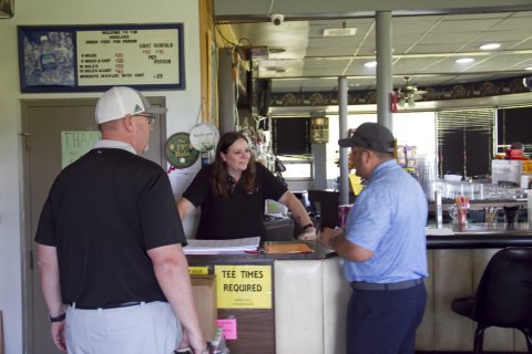 Restaurant, Cap, Person, Woman. Text: WELCOME TO THE HIGHLAND GREEN FEES PER PERSON CART RENTALS PER PERSON 18 MOLES &amp;CART MONDAYS SHOLES WITH CART adidas THAN The 19th Hole VALID TEE TIMES REQUIRED THANK YOU THE HIGHLAND