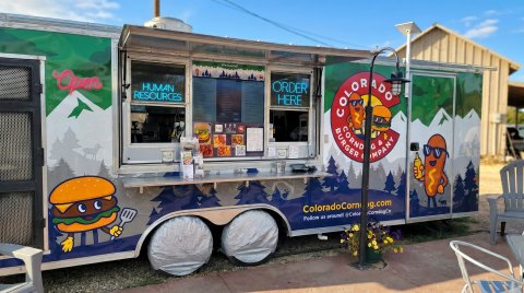 Truck, Vehicle, Chair, Food Truck. Text: Welcome! Open HUMAN ORDER RESOURCES HERE COLORADO Menu BURGER CORND MPANY G &amp; g.com ColoradoCorn CorndogCo Follow us around! @Color